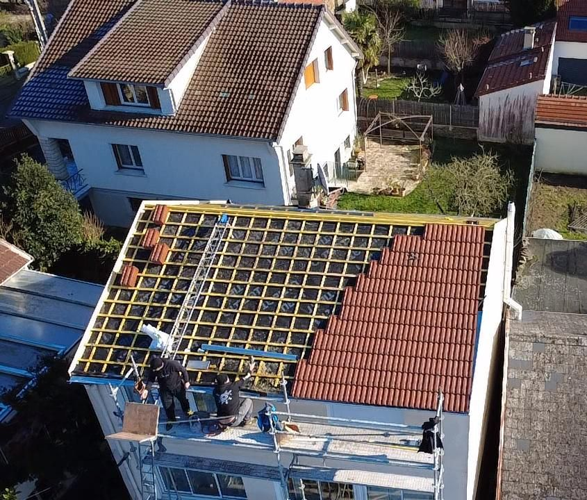 Des couvreurs remplacent les tuiles d'une toiture.