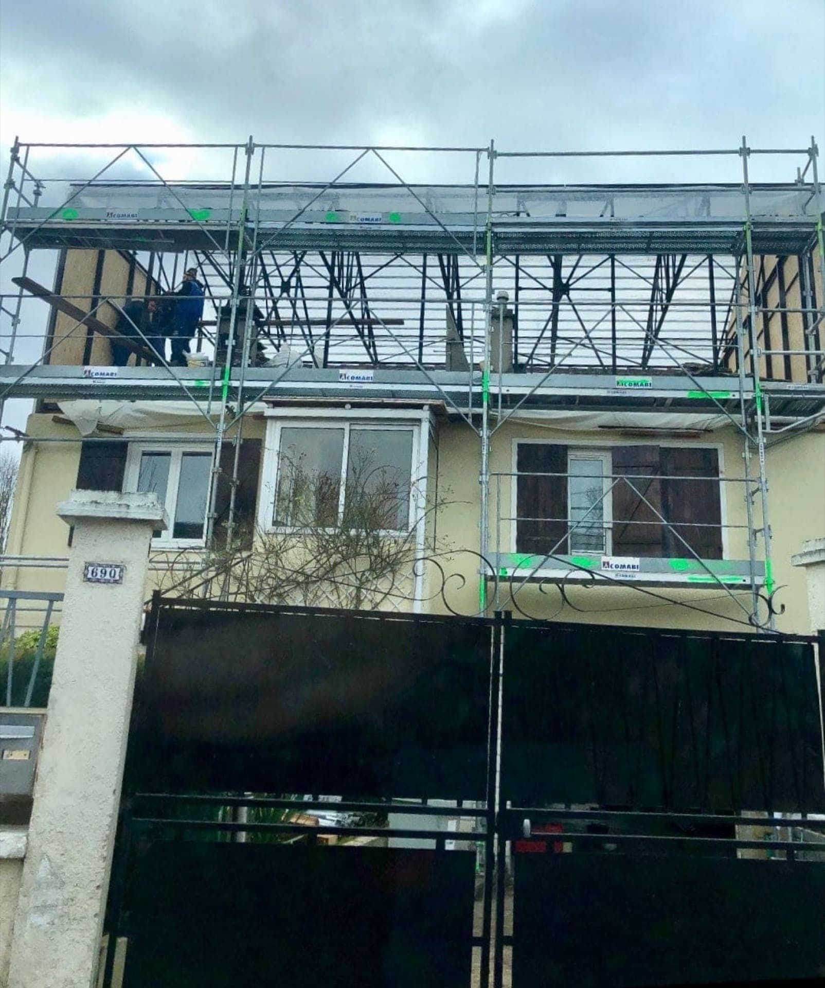 Échafaudage sur une maison en construction ; une personne travaille sur le toit.