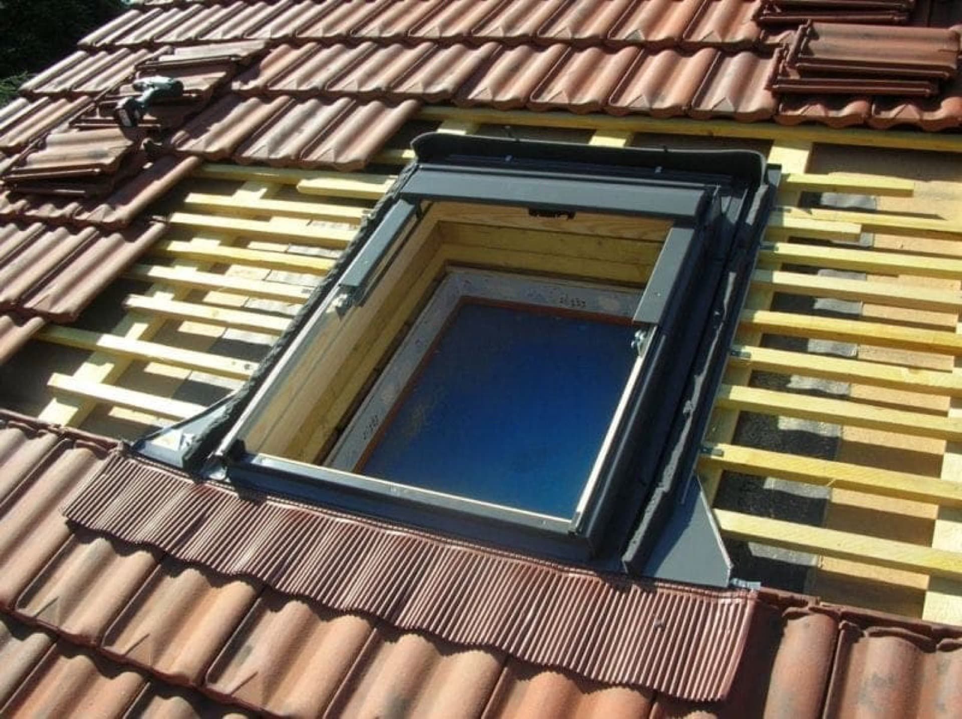 Installation d'un puits de lumière sur un toit en tuiles de terre cuite ; vue de dessus.