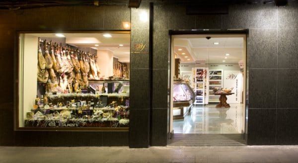 Escaparate con un gran escaparate donde se exhiben productos colgados y una entrada brillantemente iluminada por la noche.