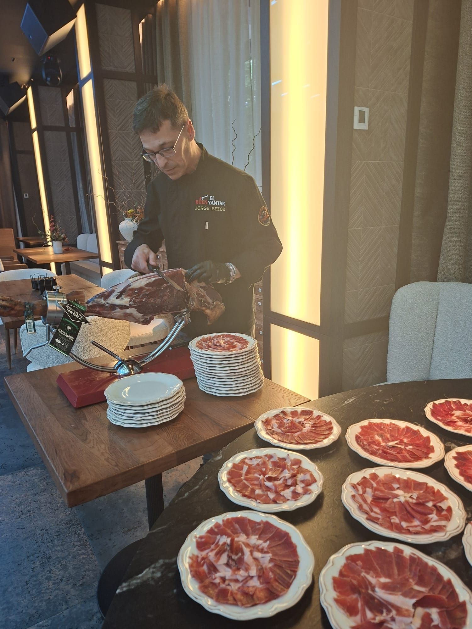 Mesa de buffet con fresas en rodajas y una persona sirviendo comida junto a una mesa de madera.