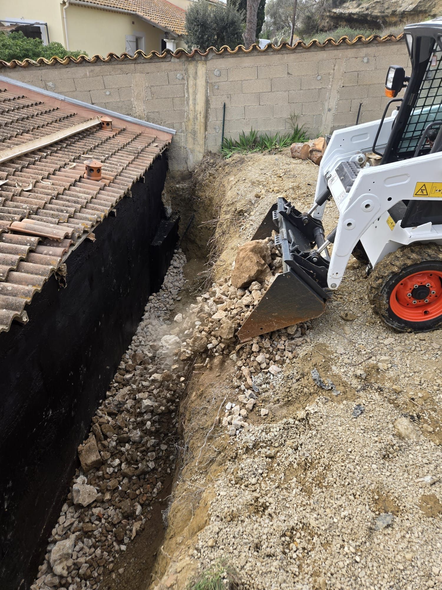 Un taille-haie repose sur une haie de jardin soigneusement taillée, avec une brouette.