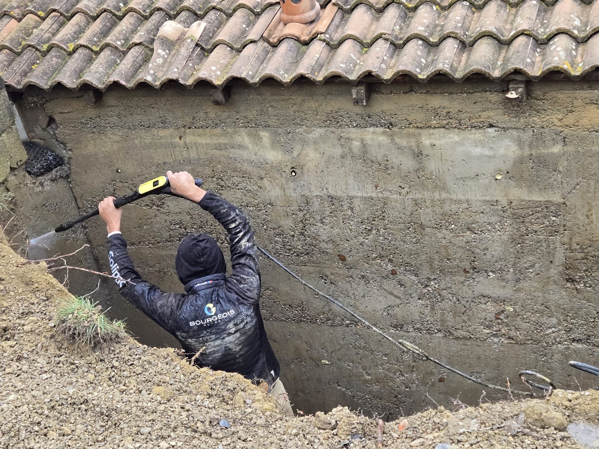 Un taille-haie repose sur une haie de jardin soigneusement taillée, avec une brouette.