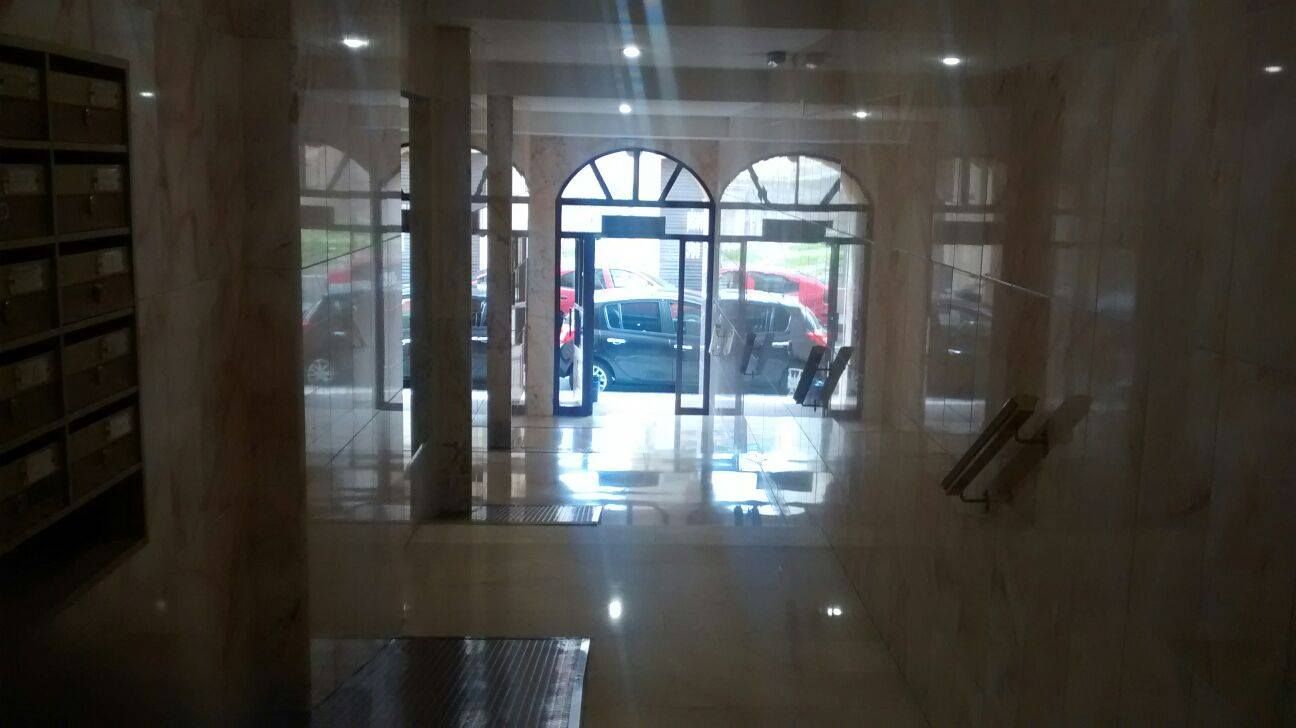 Un pasillo con suelo de mármol y una puerta corrediza de vidrio.