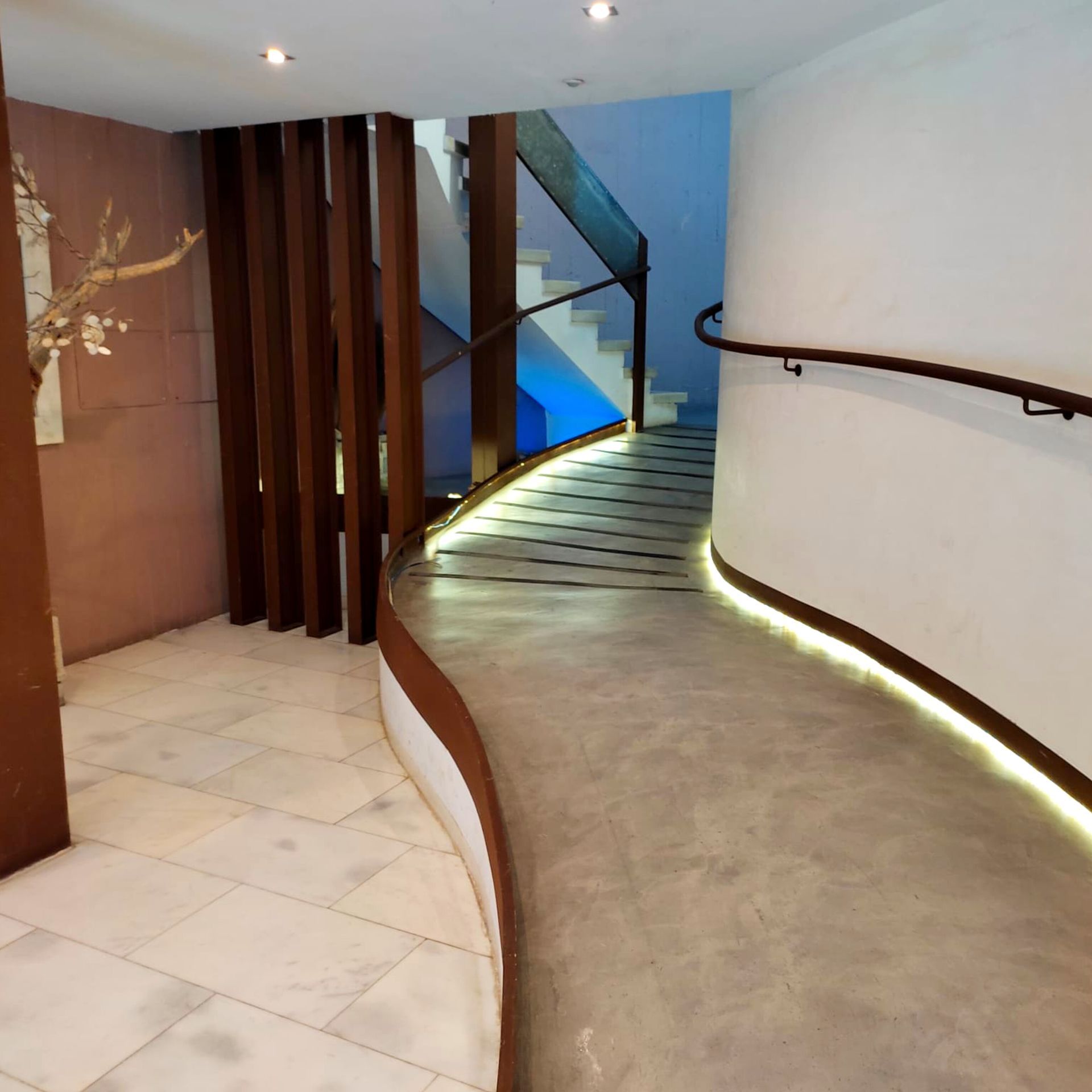 Un pasillo curvo con una escalera al fondo.