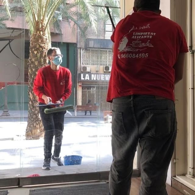 Un hombre con una camisa roja está limpiando una ventana.