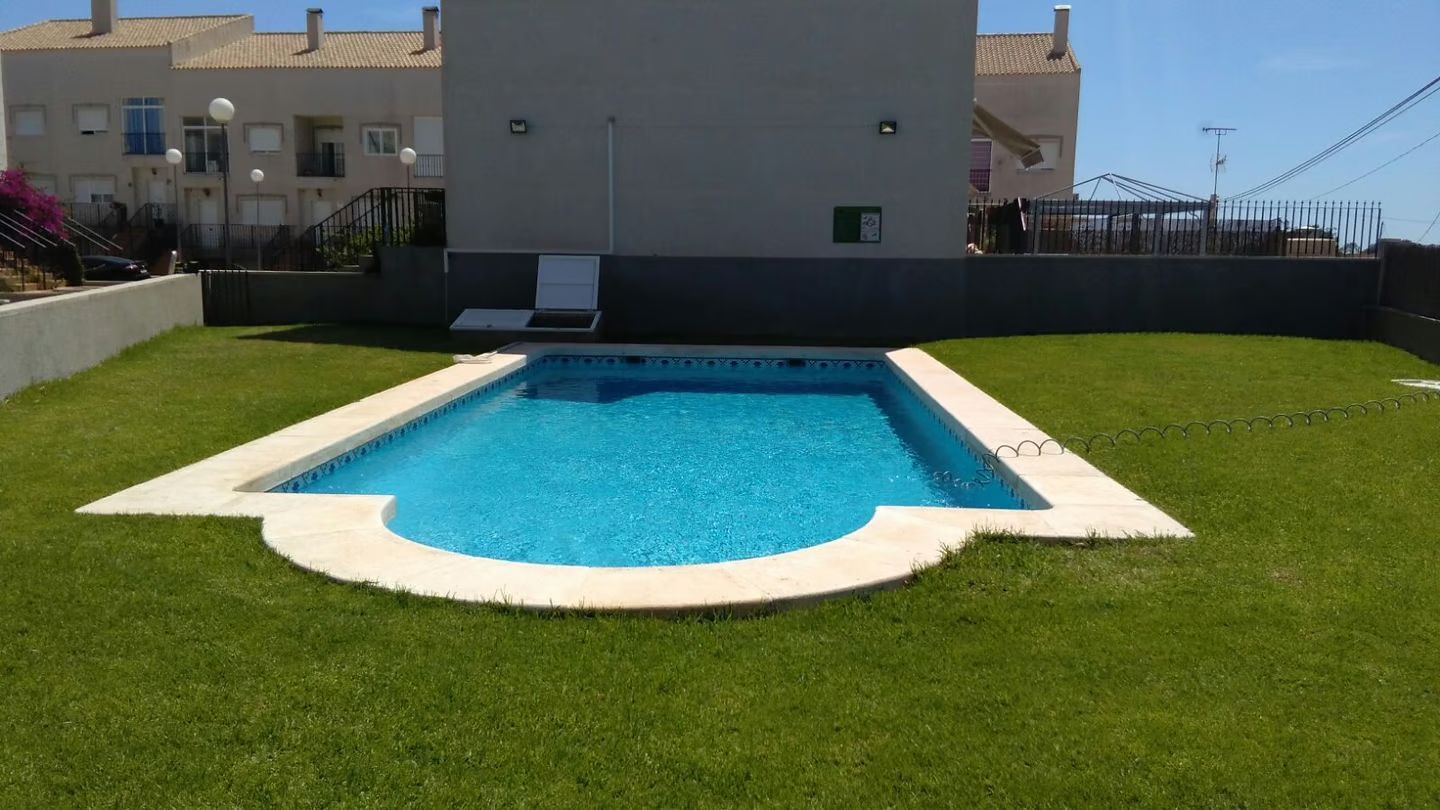 Una gran piscina está rodeada de exuberante césped verde.