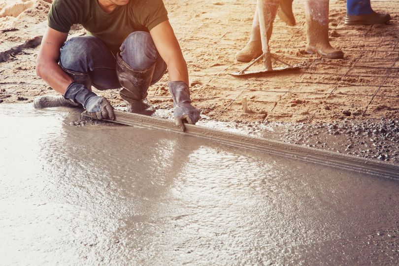 Un ouvrier lisse le béton frais d'une allée