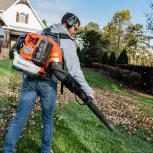 Un homme qui souffle des feuilles avec un souffleur