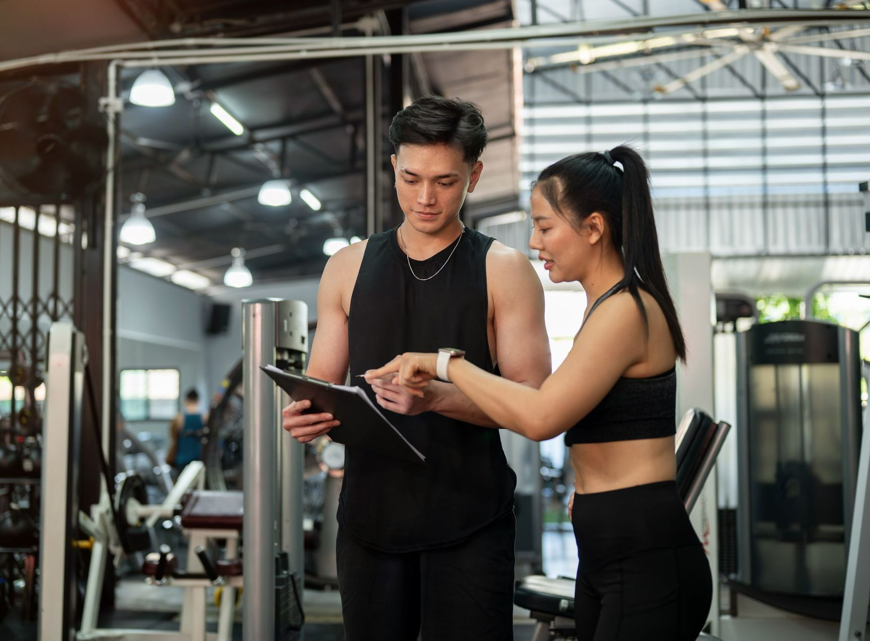 Un homme et une femme regardant un document dans une salle de sport