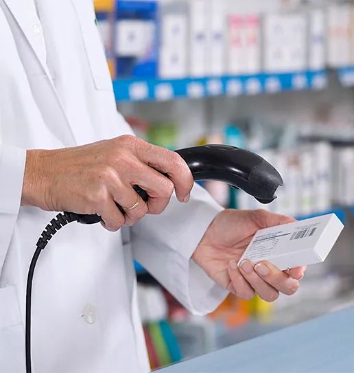 Un trabajador de farmacia está utilizando un escáner de código de barras para escanear una caja de píldoras.