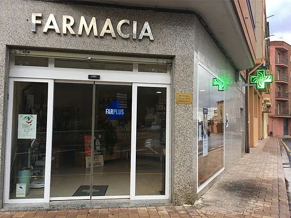 Una farmacia con una cruz verde al costado.