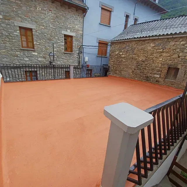 Un balcón con un edificio de ladrillo al fondo.