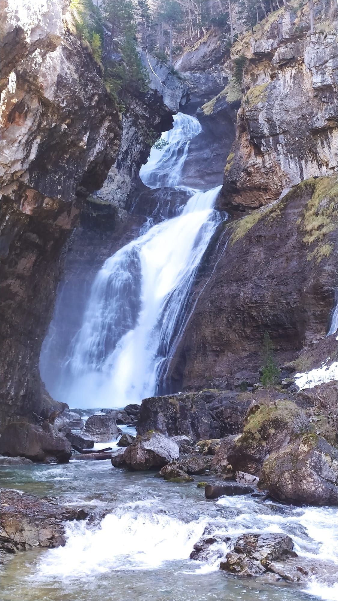 Una cascada está rodeada de rocas y un río.