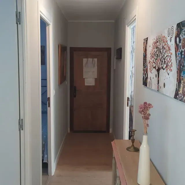 Un pasillo con una puerta de madera y un cuadro en la pared.