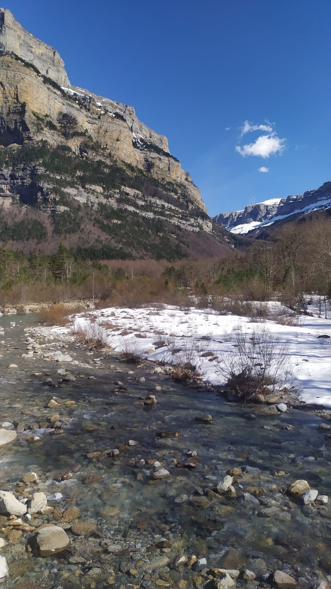 Un río que fluye a través de un valle nevado con montañas al fondo.