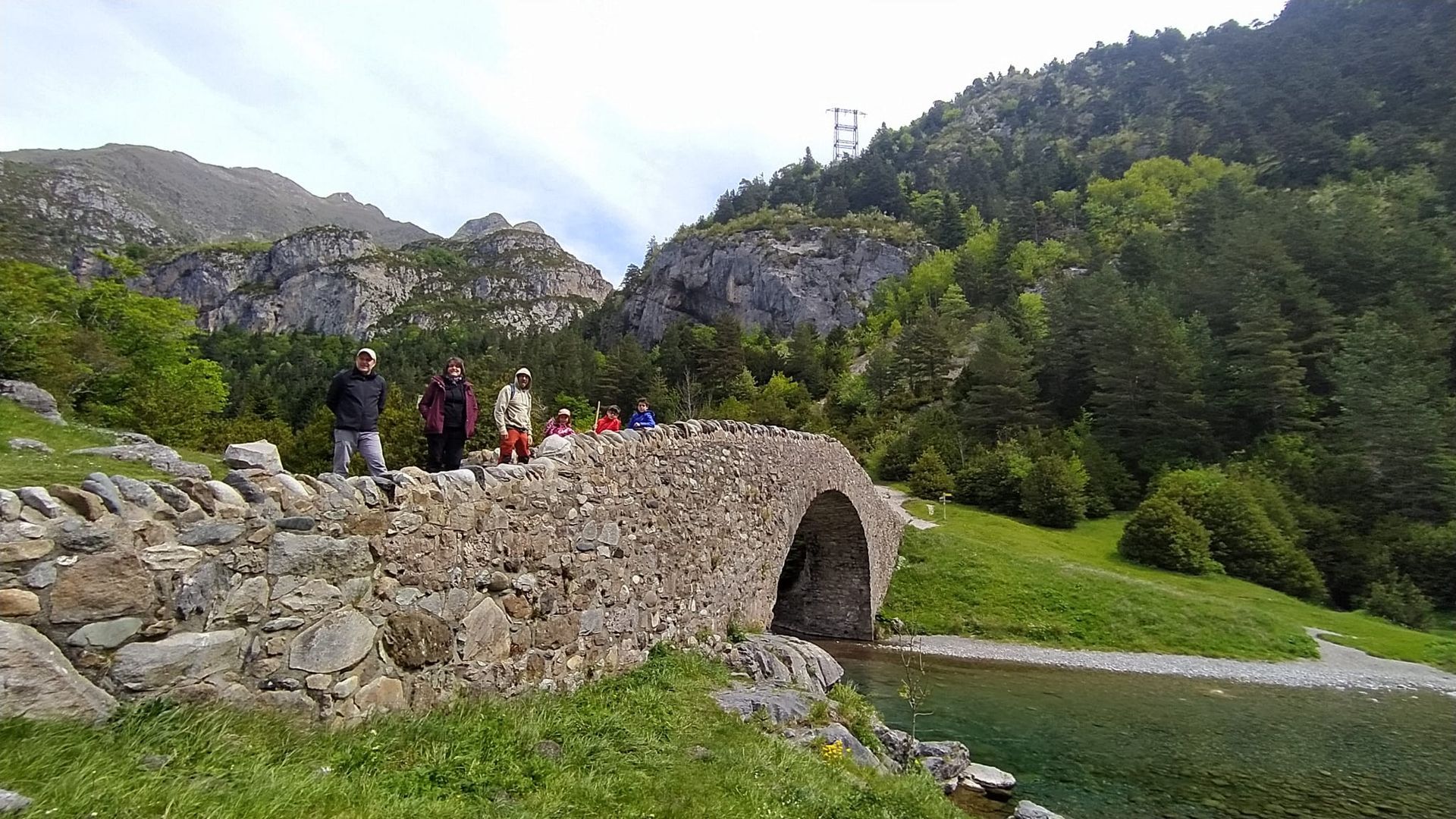 Un grupo de personas está de pie en un puente de piedra sobre un río.
