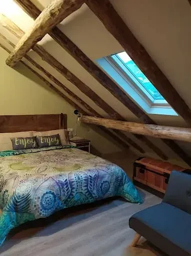 Hay una cama en el ático con una claraboya.
