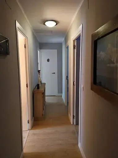 Un largo pasillo con una cómoda y un cuadro en la pared.