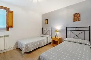 Un dormitorio con dos camas, una mesita de noche y una ventana.