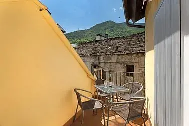 Un balcón con una mesa y sillas y montañas al fondo.