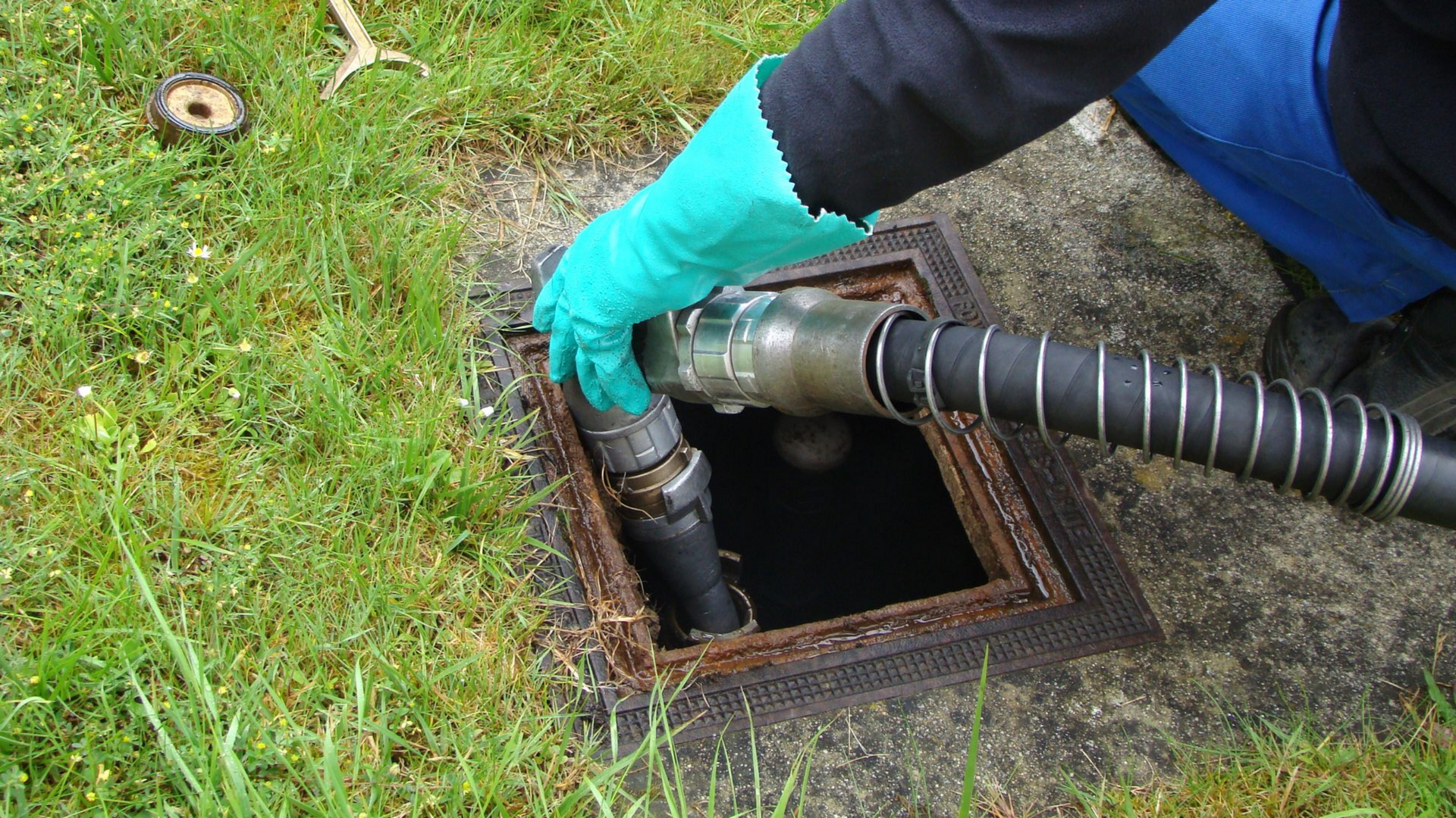 Une personne portant un gant vert raccorde un tuyau de carburant à une cuve souterraine.