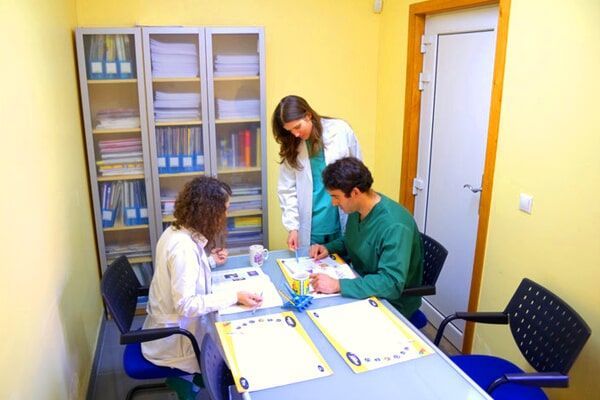 Um grupo de pessoas está sentado em redor de uma mesa num gabinete de consultas.