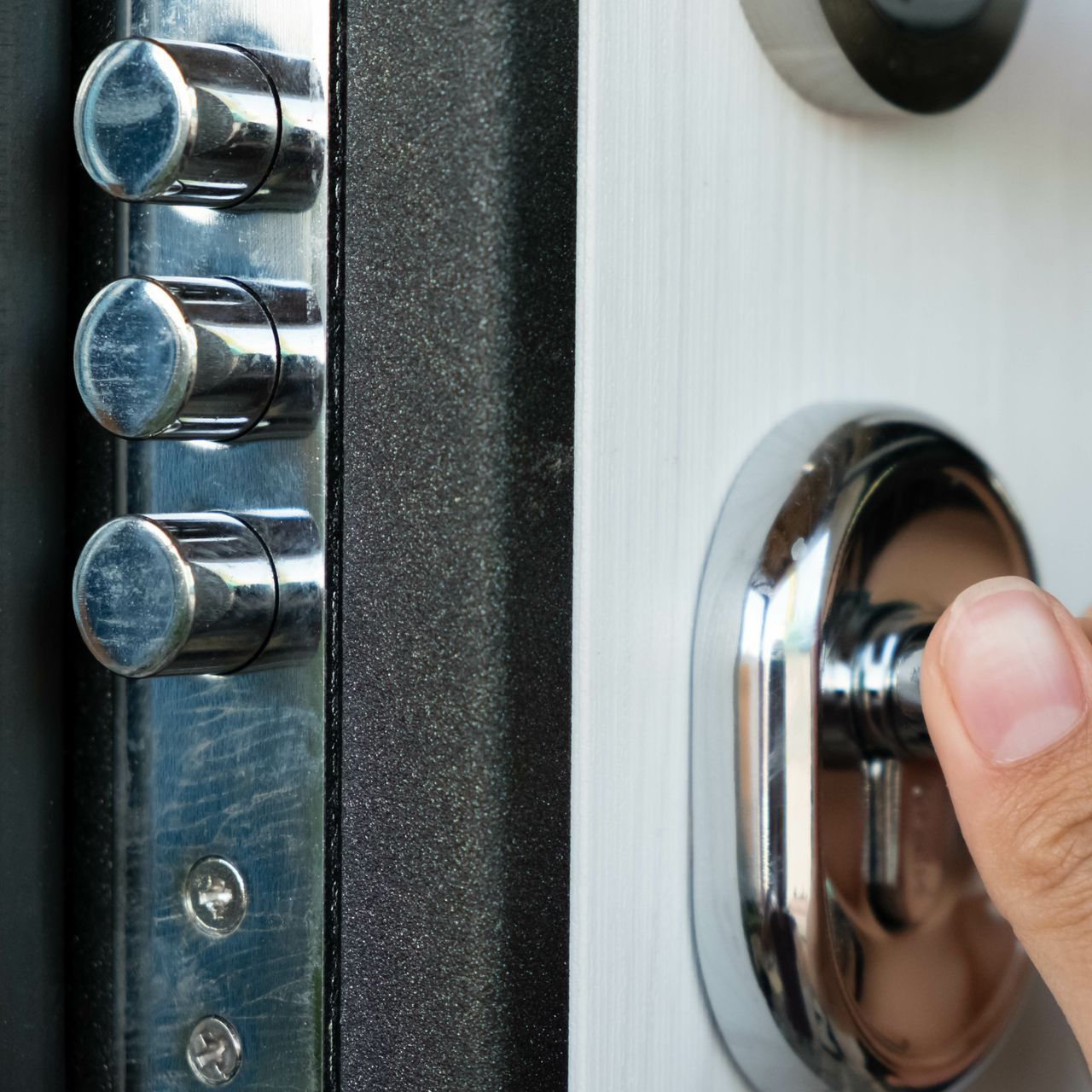 Gros plan sur une serrure de porte à trois pênes et une personne tournant la clé dans la poignée.