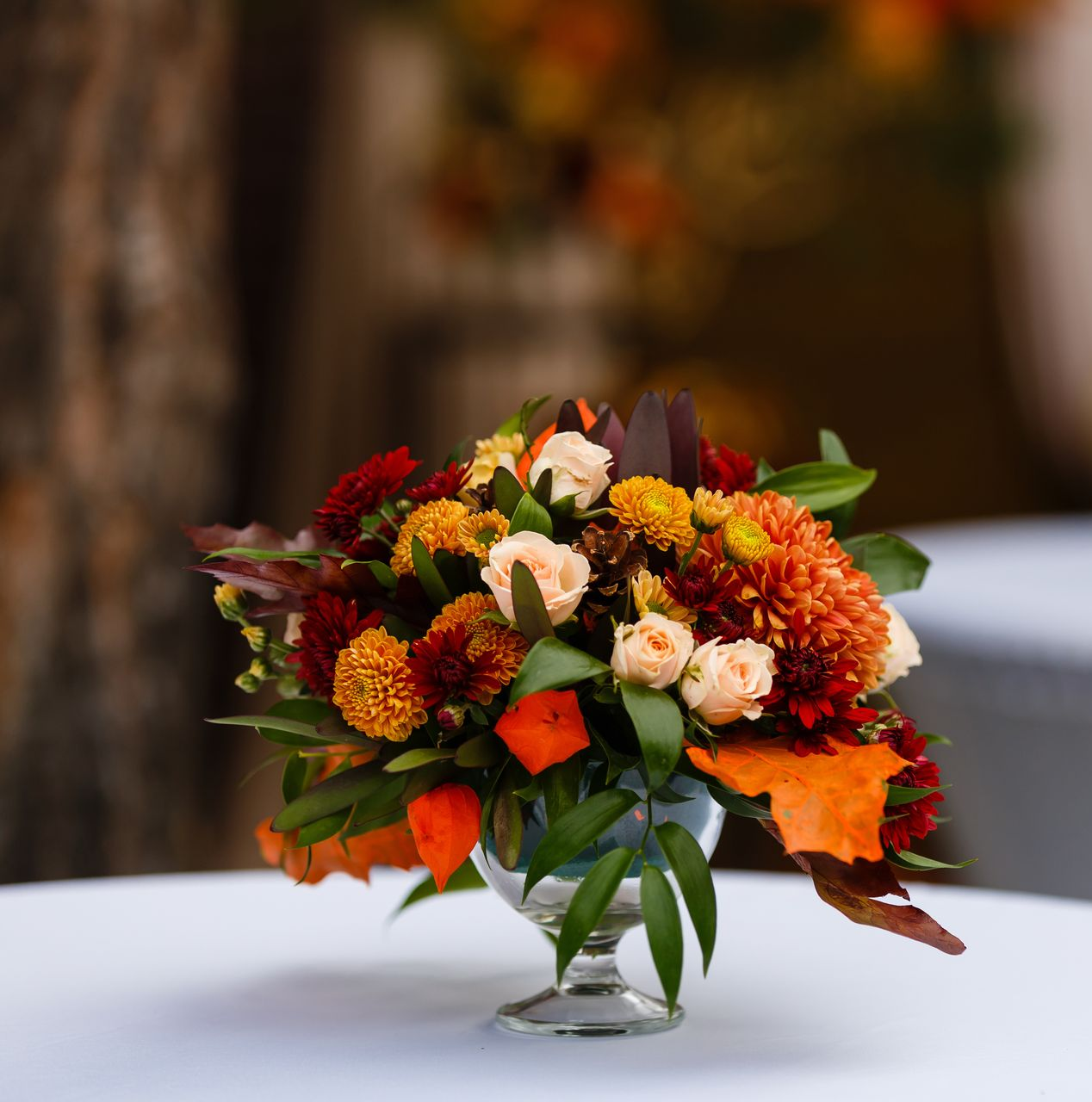 Composition florale automnale colorée avec des fleurs orange, rouges et blanches.