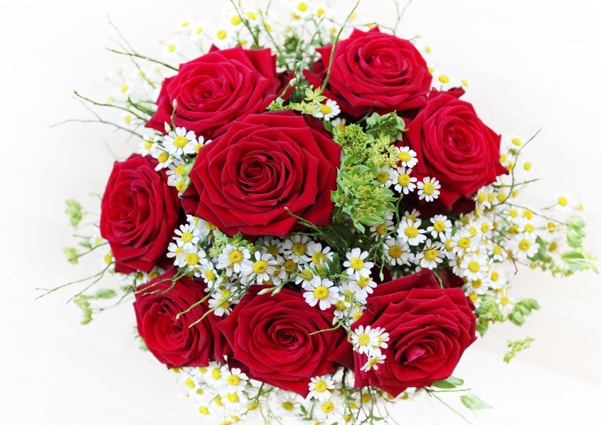 Roses rouges et marguerites blanches disposées en bouquet.