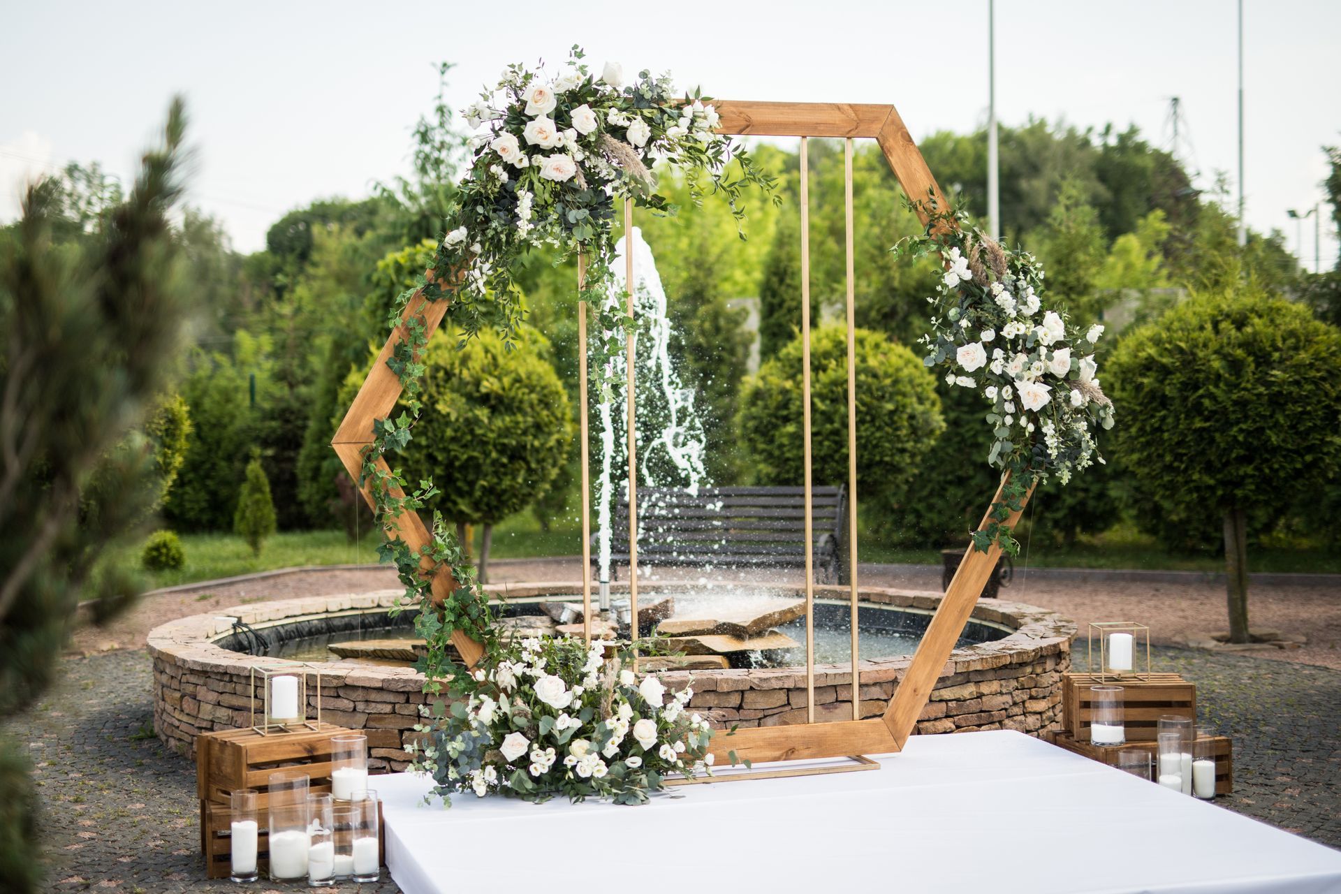 Arche de mariage extérieure ornée de fleurs blanches et d'une fontaine dans un cadre de jardin