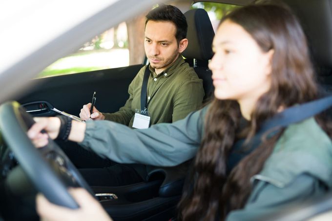 Instructor instruyendo a un alumno en un coche durante una clase de conducción