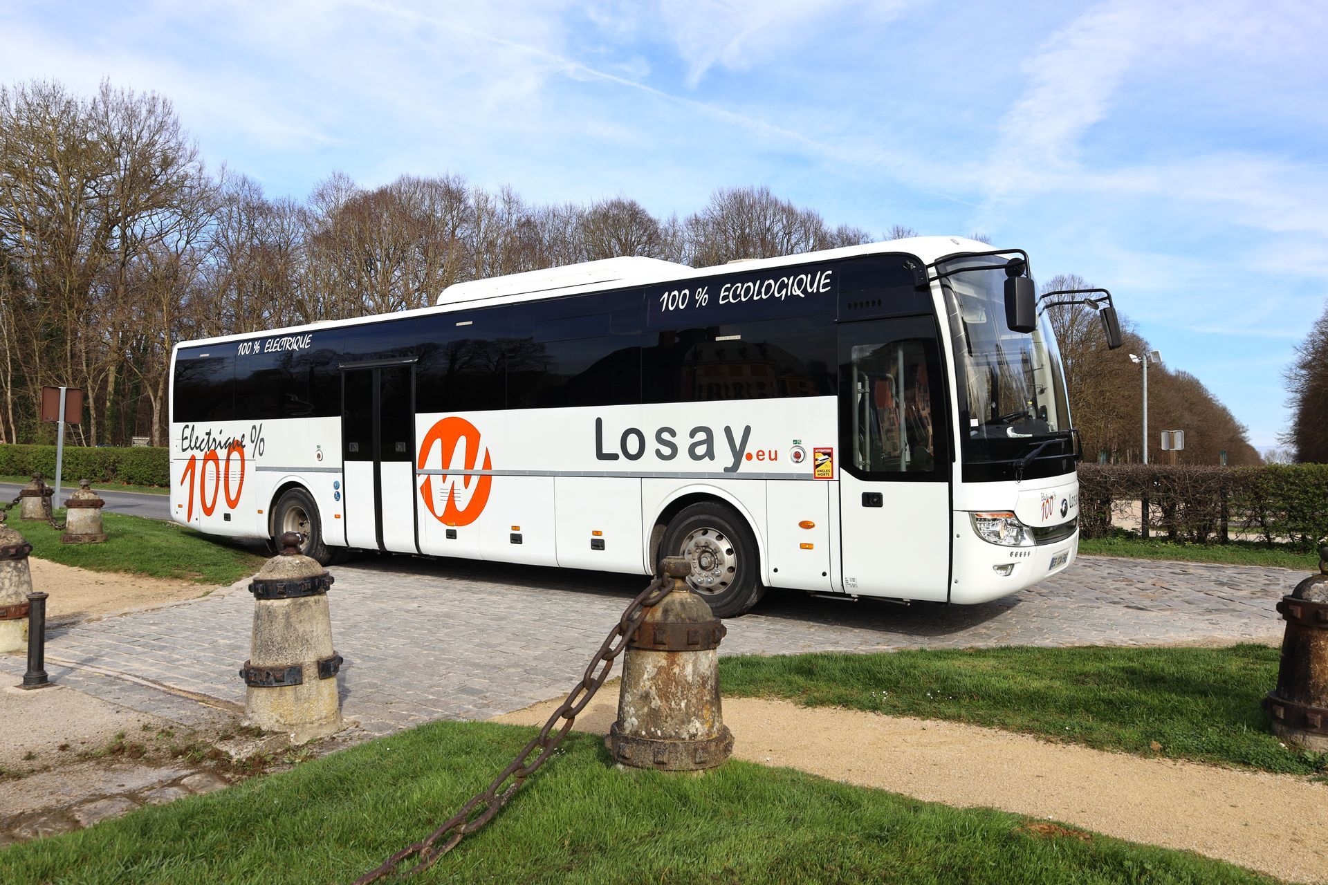 Autocar 100% électrique stationné devant une entrée d'un monument important