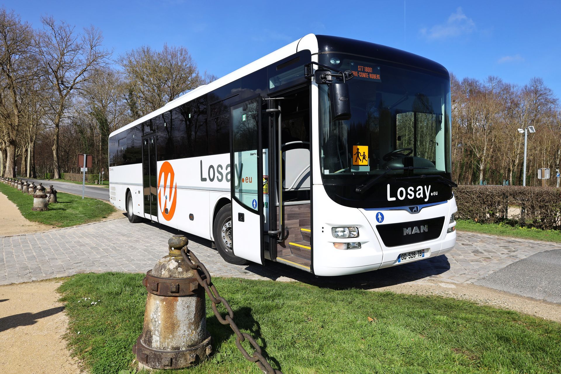 Autocar avec porte conducteur ouverte garé sur des pavets