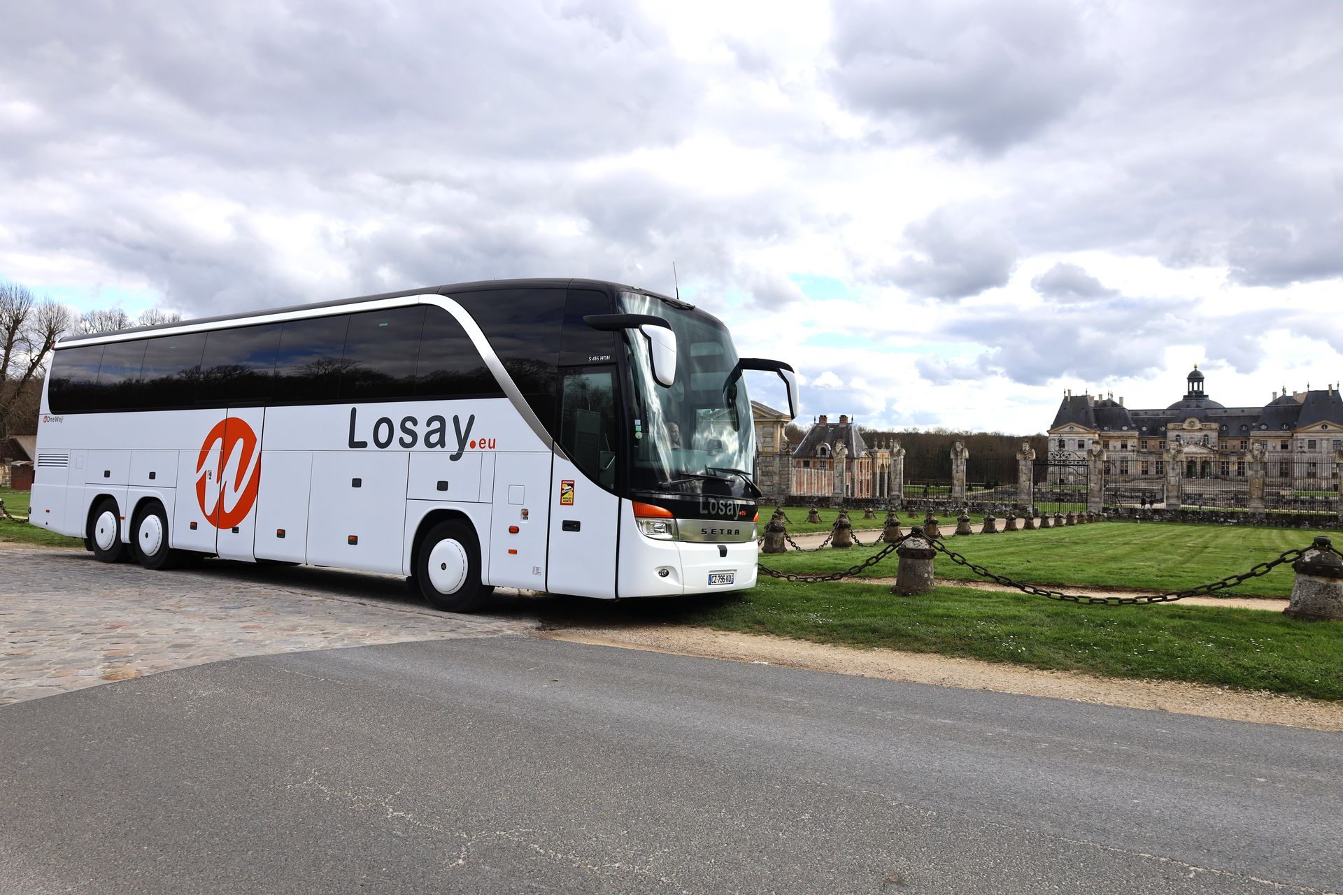 Autocar stationné devant un château en campagne 