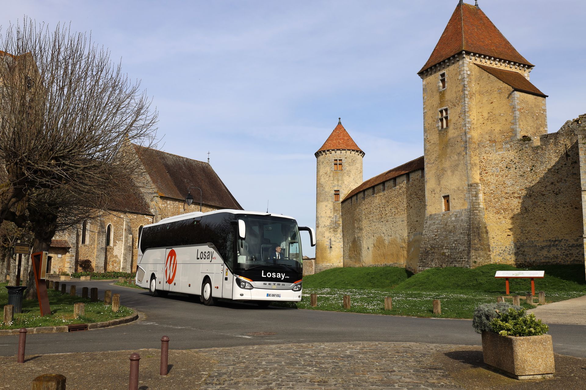 Bus Losay Voyages devant un château médiéval dans un village