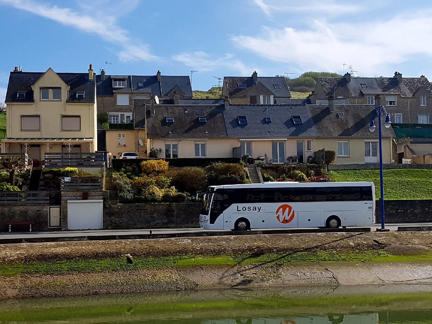 Autocar en balade sur une route de campagne avec des maisons individuelles en fond