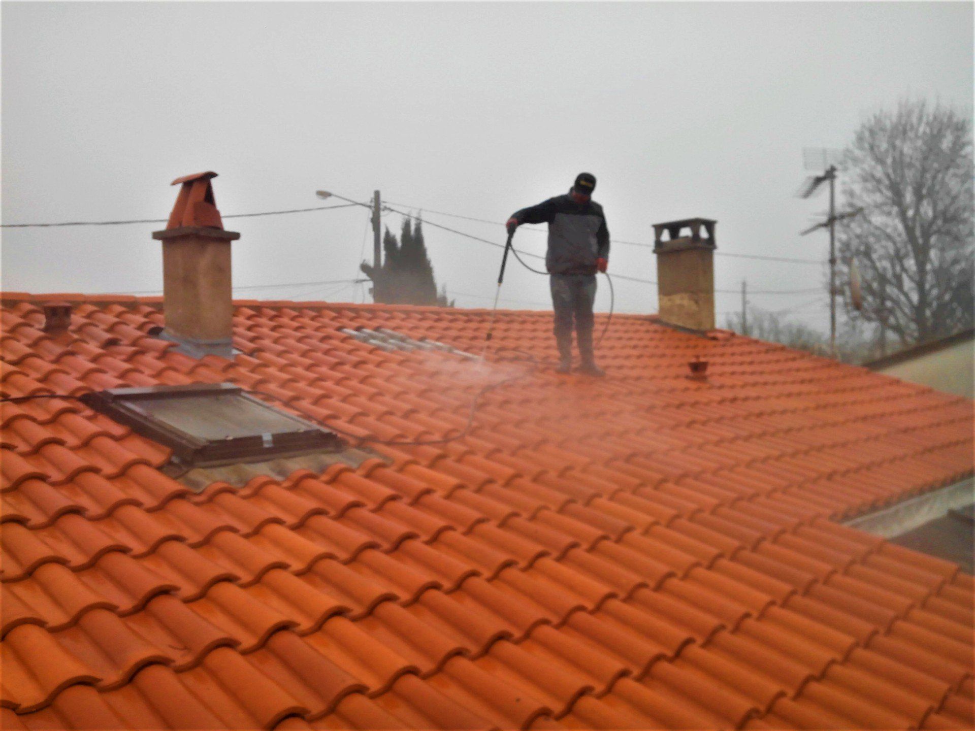 Toiture en cours de nettoyage avec pulvérisateur à pression