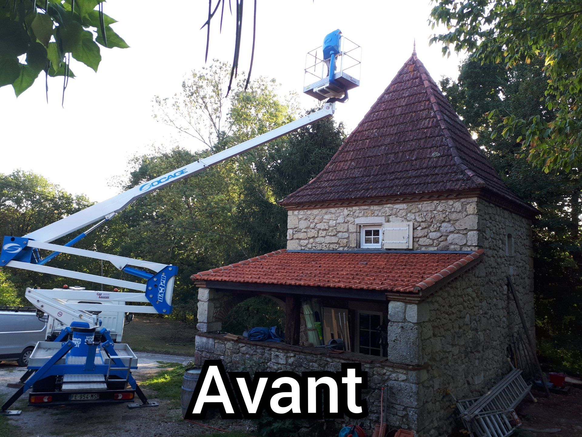 Démoussage d'une toiture très pentue à l'aide d'une nacelle pour un bâtiment en pierre, photo avant travaux