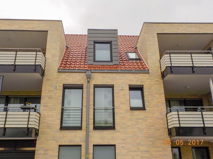 Ein Backsteingebäude mit Balkonen und einem roten Dach.