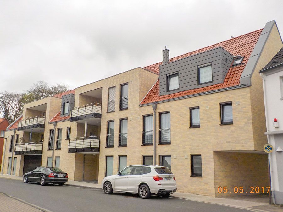 Ein weißes Auto parkt vor einem großen Backsteingebäude.