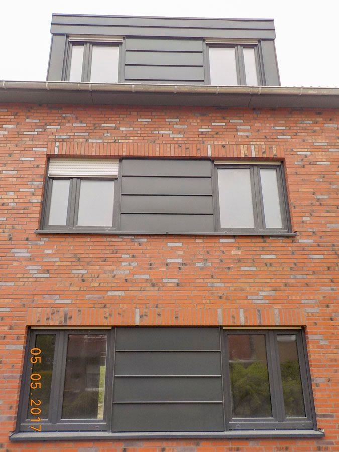 Ein Backsteingebäude mit vielen Fenstern und einem schwarzen Dach.