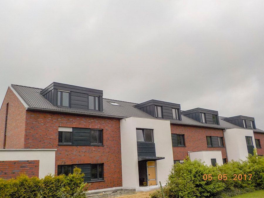 Eine Reihe von Backsteinhäusern mit einem grauen Himmel im Hintergrund.