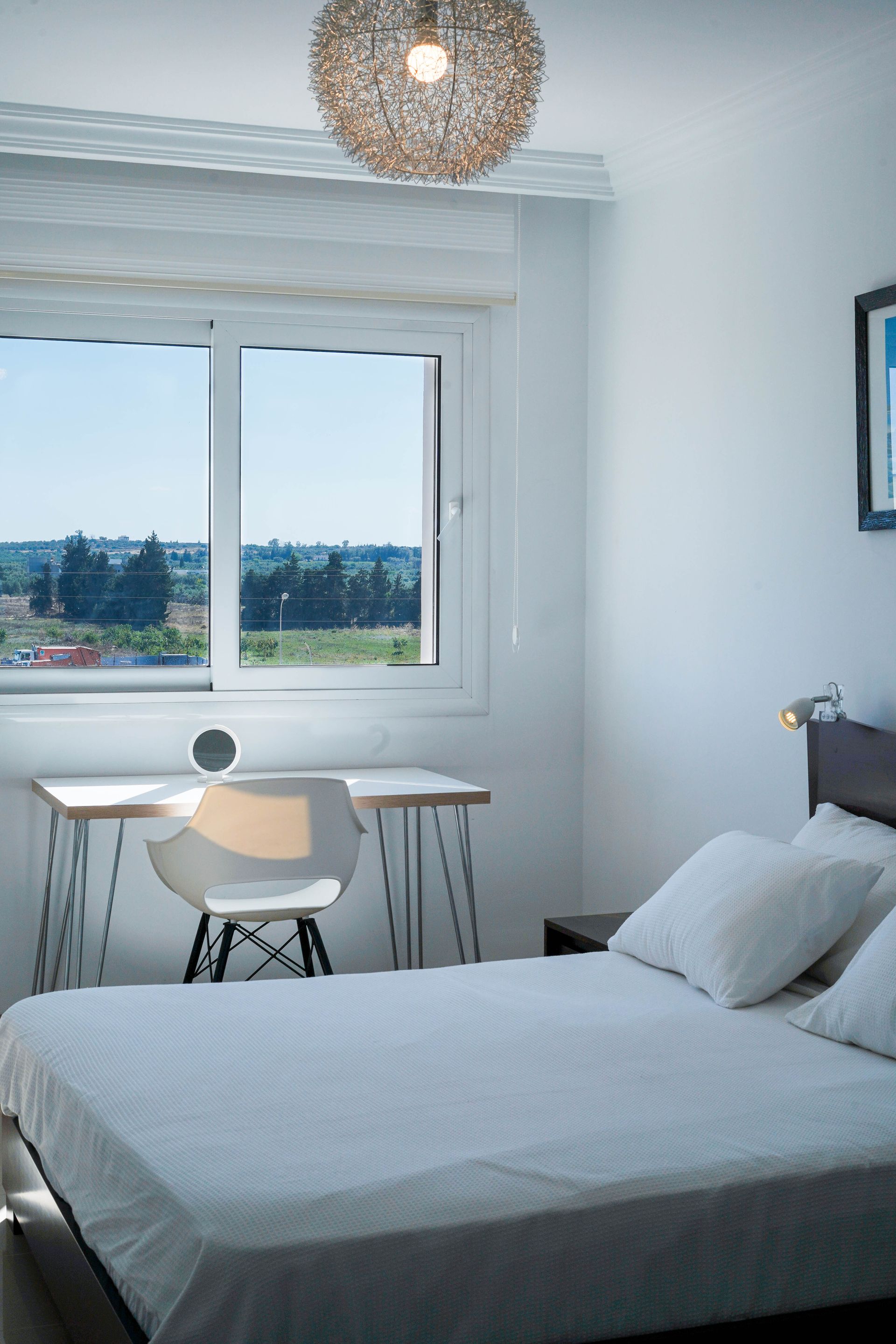 Bedroom with a bed, desk, chair, and window overlooking a landscape.