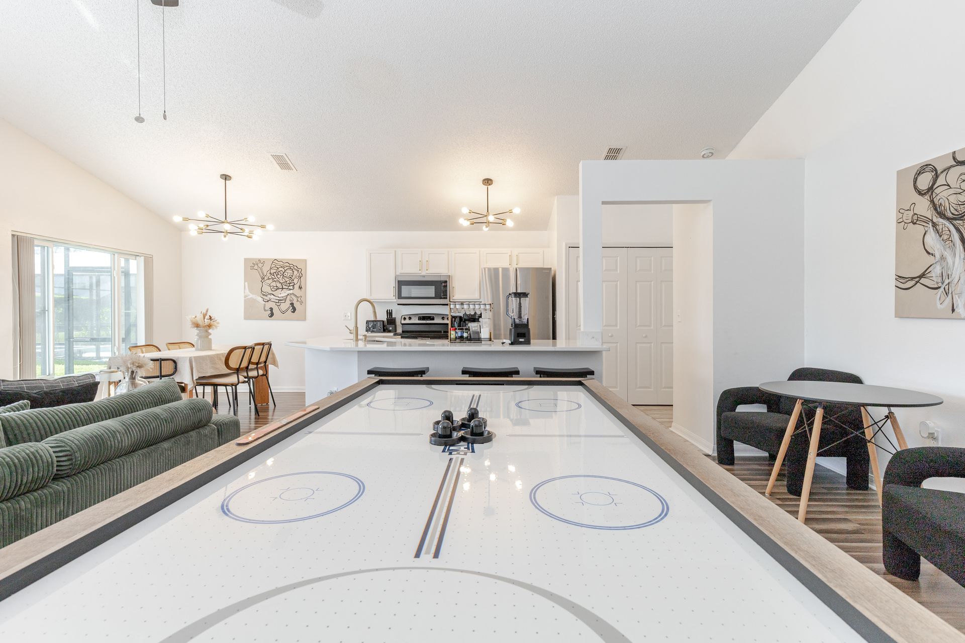 Air hockey table in a modern living space, kitchen and dining in the background.