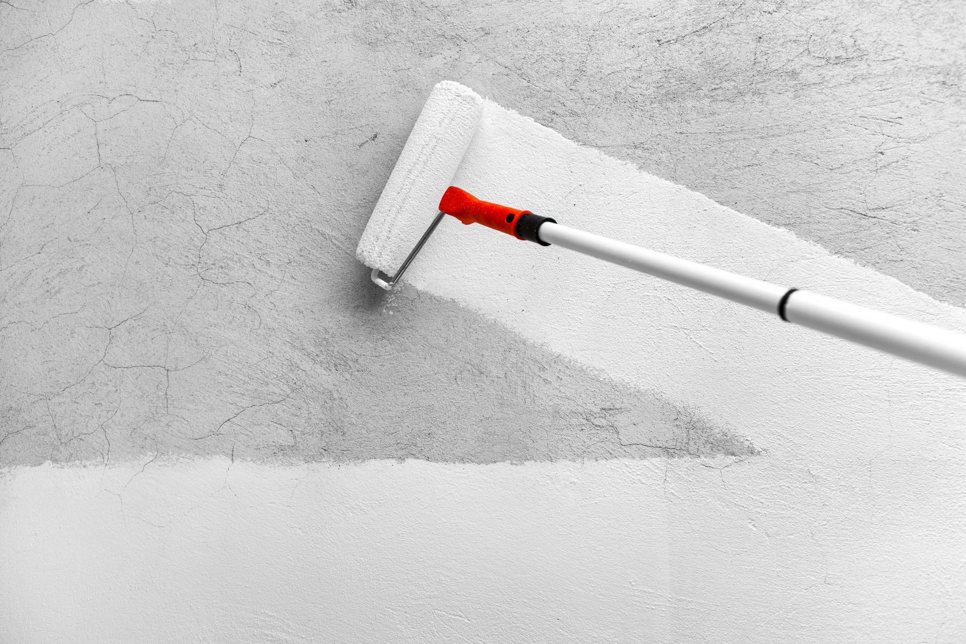 Passage de peinture blanche au rouleau sur un mur gris