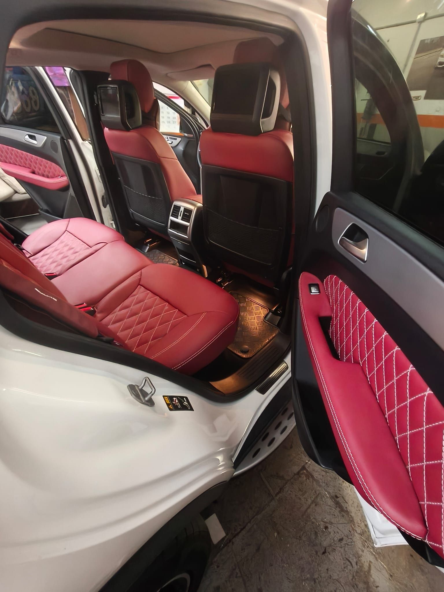 Interior del coche con fundas de asiento acolchadas personalizadas en rojo y rosa y paneles de puerta a juego.