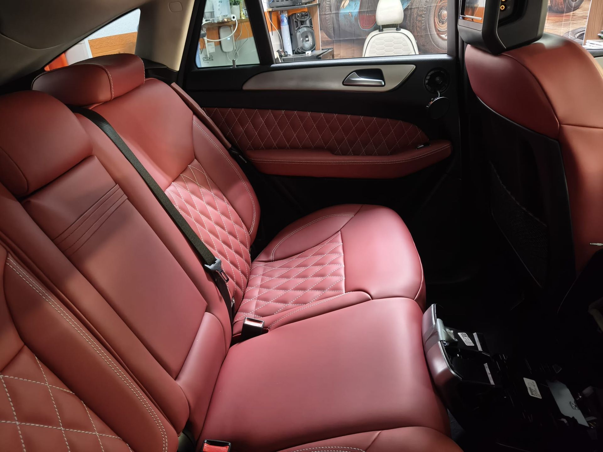 Asiento trasero de coche de cuero rojo con costuras en forma de diamante y ventanas tintadas