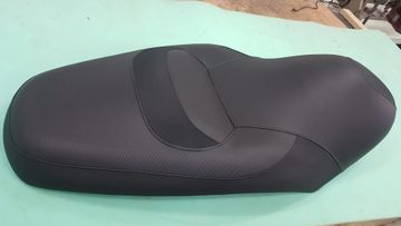 Asiento de motocicleta negro sobre una superficie verde menta.
