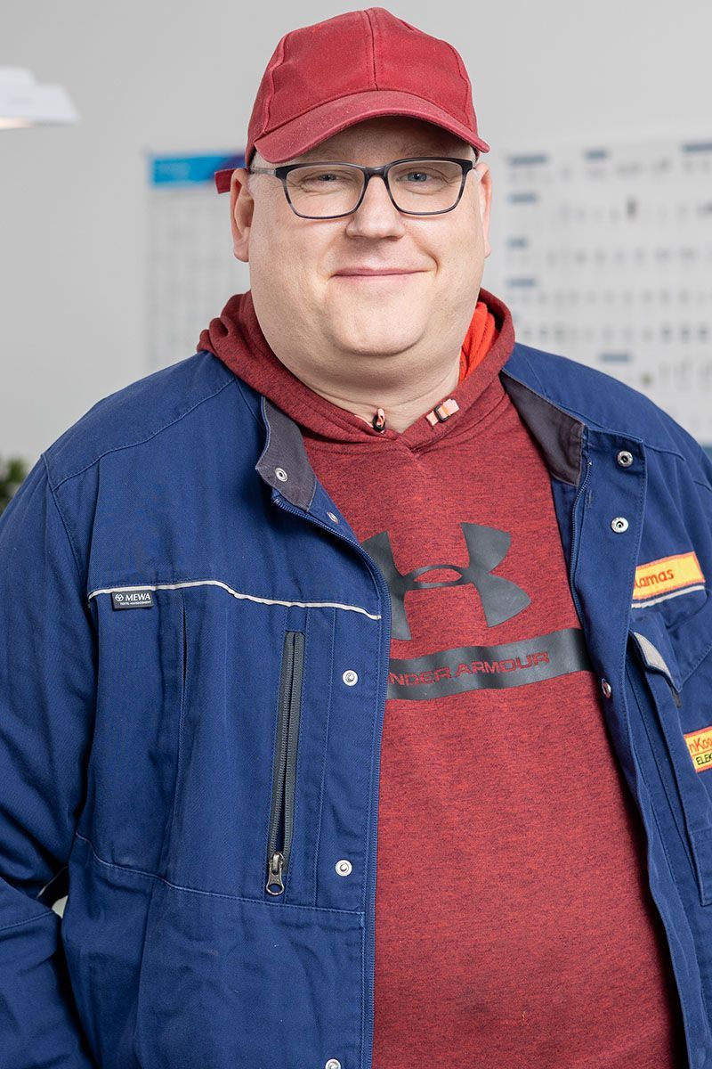 Ein Mann mit einer blauen Jacke und einem roten Hut steht in einem Raum.